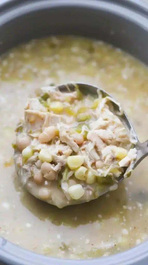 Close up spoonful of creamy Green Chile Chicken Enchilada Soup with chicken, beans, and corn