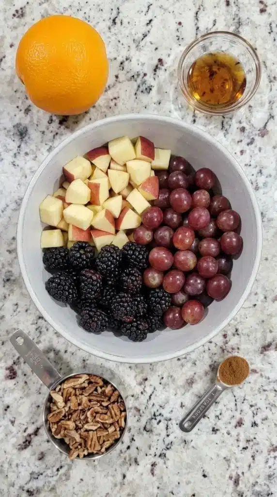 Fall Fruit Salad ingredients with apples, grapes, blackberries, pecans, and maple syrup