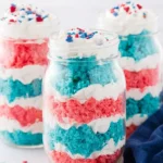 Fourth of July cake in a jar with colorful red blue cake layers and whipped topping