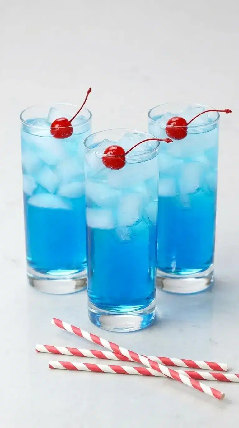 Blue Fourth of July cocktail with cherries and ice in tall glasses on a rustic summer table