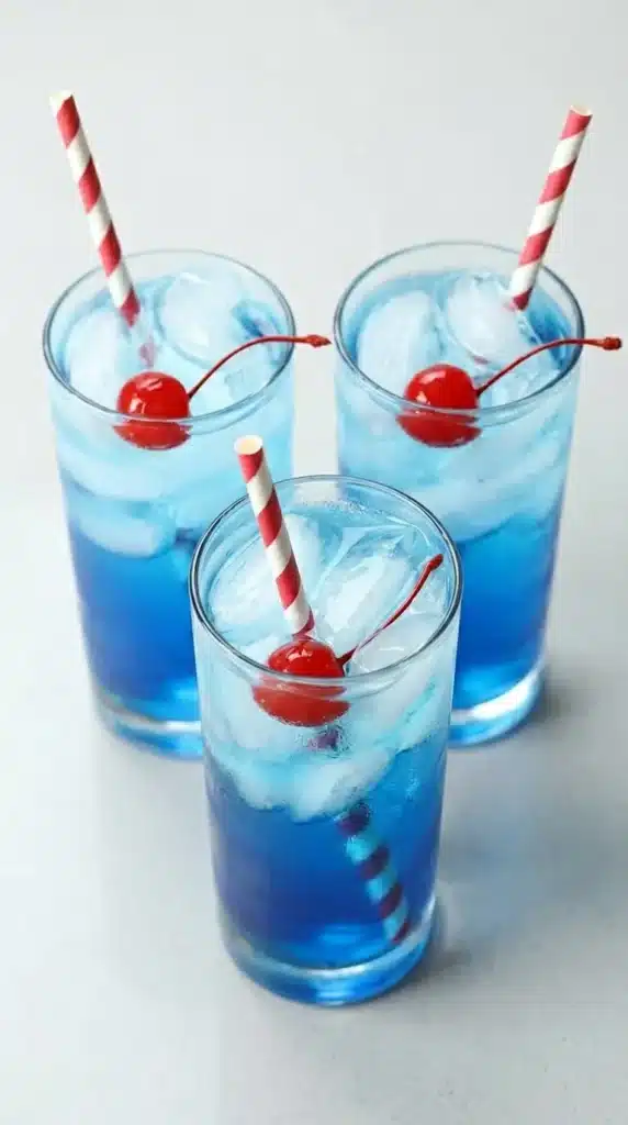 Fourth of July Cocktail with blue drink, ice, cherries, and striped straw