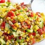 Fresh corn salad with tomatoes, cucumber, and herbs in a bowl