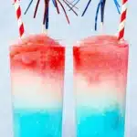 Frozen Bomb Pop Cocktail with red white and blue layered slushy texture in tall glasses
