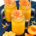 Creamy ginger peach smoothie in a glass jar with fresh peaches and colorful summer styling