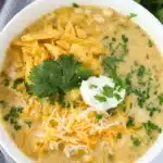 Creamy Green Chile Chicken Enchilada Soup topped with cheese, tortilla strips, and cilantro