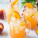 Homemade peach lemonade with fresh peaches and ice in glass tumblers