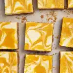 Mango cheesecake bars with creamy filling and glossy mango swirl topping