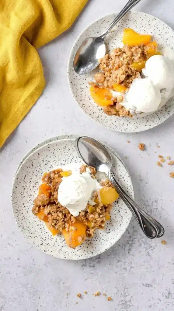 Peach Crisp with Canned Peaches served with vanilla ice cream on ceramic plates
