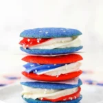 Red white and blue cookie sandwiches with patriotic buttercream frosting and star sprinkles