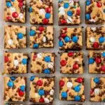 Red, white and blue M&M cookie bars with chocolate chips on parchment paper