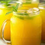 Refreshing homemade mango lemonade with mint leaves and ice in glass jars