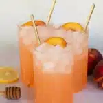 Refreshing peach lemonade in tall glasses with ice and fresh peach slices