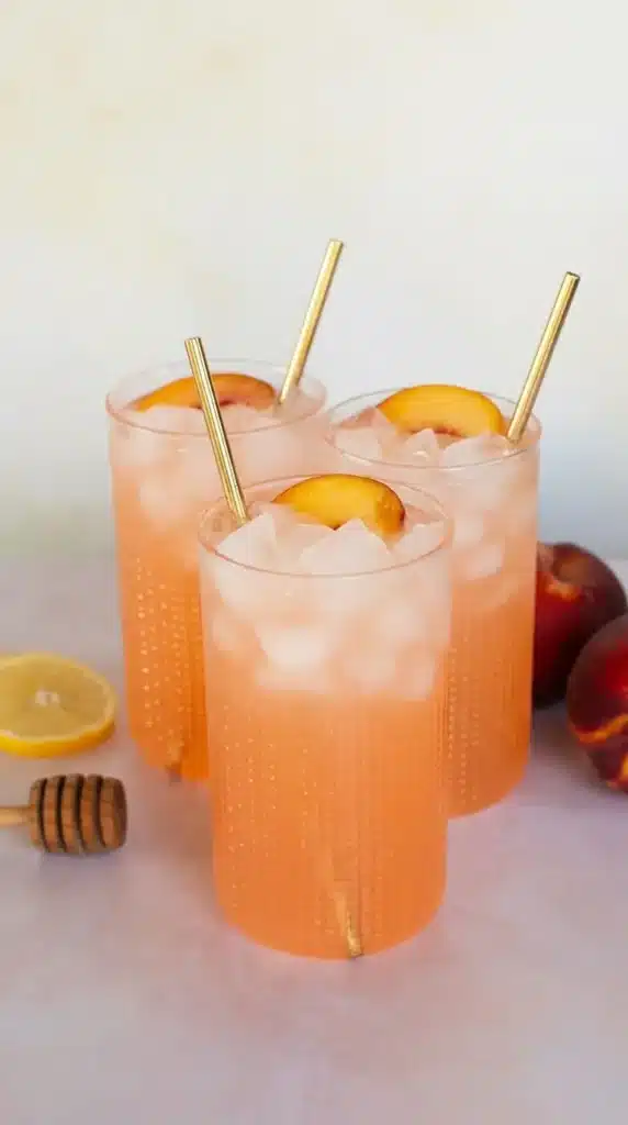 Refreshing peach lemonade in tall glasses with ice and fresh peach slices