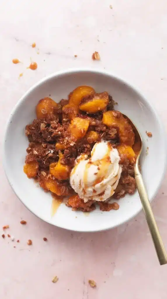 Sheet Pan Peach Crisp served with vanilla ice cream in white bowls