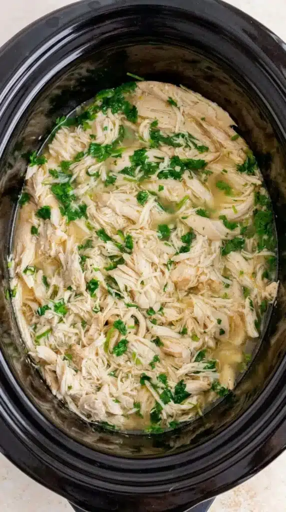 Slow cooker cilantro lime chicken with shredded chicken and fresh cilantro in savory lime broth