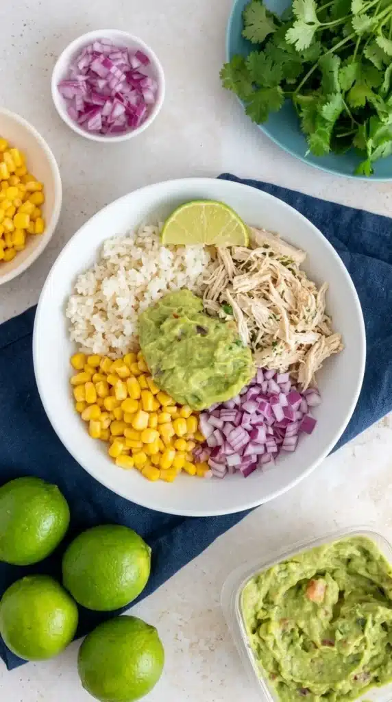 Slow Cooker Cilantro Lime Chicken rice bowl with corn, guacamole, rice, and lime