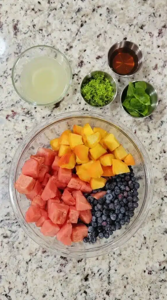 Summer Fruit Salad ingredients with watermelon, peaches, blueberries, lime, honey, and basil