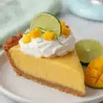 Tropical mango key lime pie slice with whipped cream and lime garnish