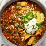Vegan black bean chili topped with avocado, jalapeños, and crispy corn chips