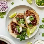 Vegan slow cooker lentil tacos with cilantro, jalapeños, and lime on charred tortillas