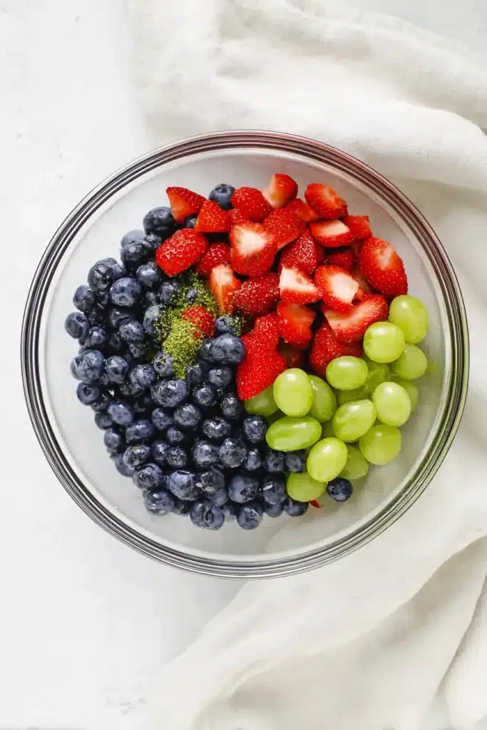 Honey Lime Fruit Salad ingredients combined in a mixing bowl before tossing