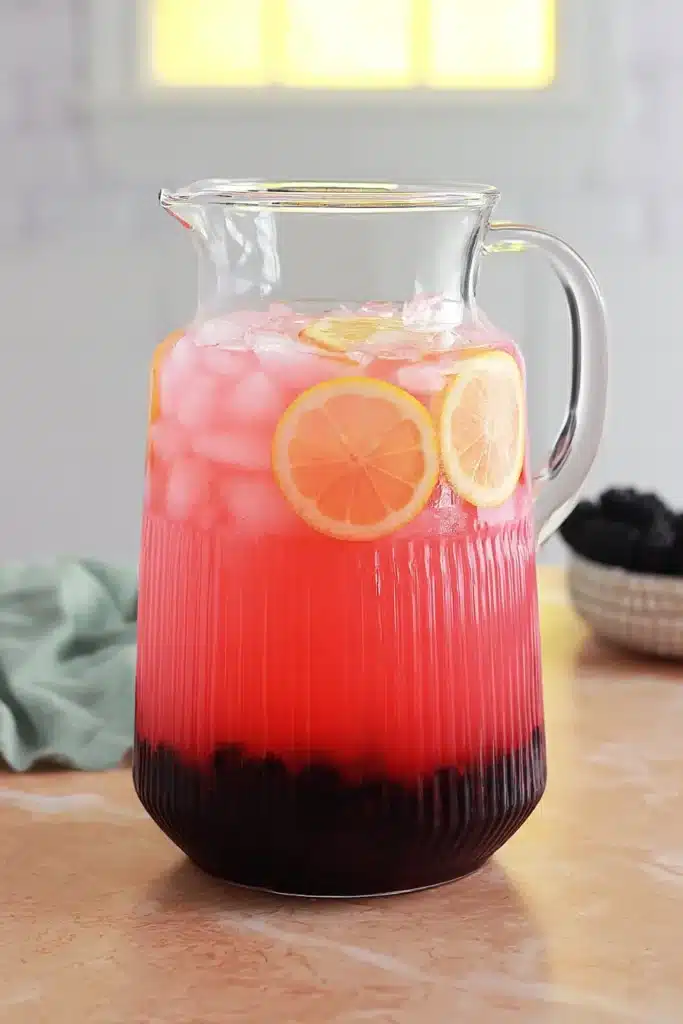 Blackberry Lemonade Recipe in a glass pitcher with lemon slices and ice