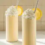 Copycat Chick-fil-A Frosted Lemonade Easy Amazing Treat 5 Copycat Chick-fil-A Frosted Lemonade in tall glasses with whipped cream and fresh lemon garnish