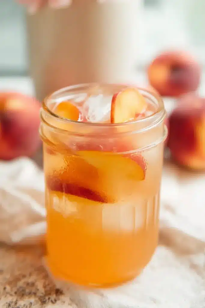 Homemade Peach Lemonade Easy Amazing Summer Favorite 6 Homemade Peach Lemonade served with ice and fresh peach slices in a mason jar