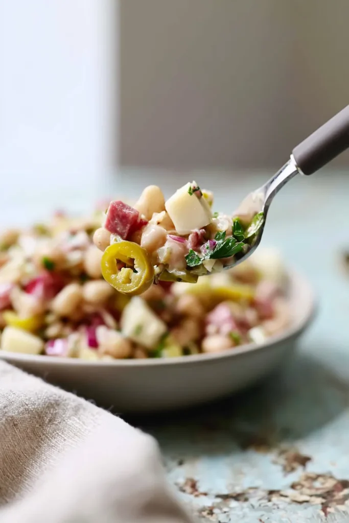 Forkful of Italian Grinder Bean Salad with beans, salami, cheese, and pepperoncini