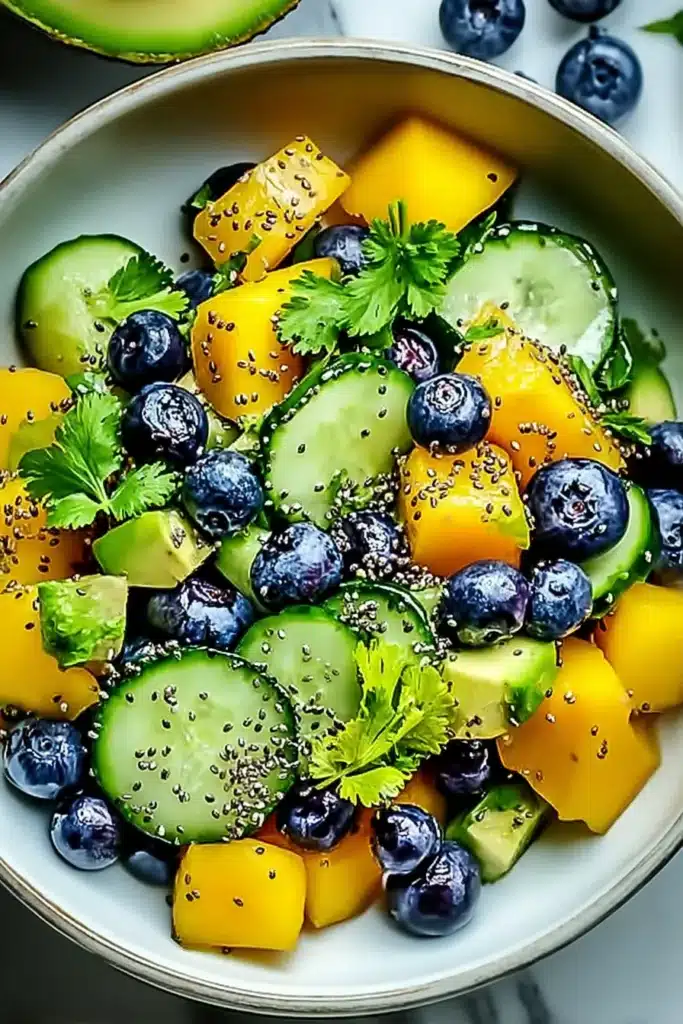 Juicy Mango Cucumber Salad Recipe | Amazing Fresh Flavor 4 Juicy Mango Cucumber Salad with blueberries and avocado in a ceramic bowl