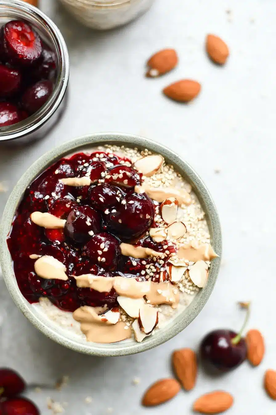 Oats with Cherry Chia topped with cherry jam, almond butter, and fresh cherries