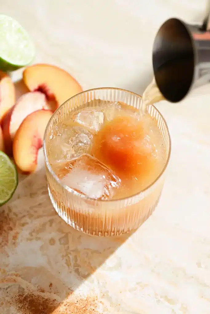 Peach Moscow Mule cocktail with fresh peach slices and lime garnish