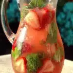 Fresh strawberry basil lemonade in a glass pitcher with sliced strawberries and basil
