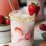 Strawberry Coconut Refresher in a mason jar with fresh strawberries, coconut rim, and ice cubes