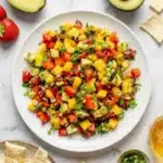 Fresh Avocado Strawberry Mango Salsa served with crispy pita chips in a ceramic bowl.