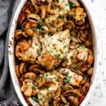 Baked Chicken with Mushrooms topped with melted mozzarella in a rustic baking dish