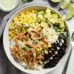 Chicken Burrito Bowl with shredded chicken, rice, black beans, corn, avocado, cheese, and cilantro.