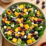 Mango Spinach Salad with blueberries, feta cheese, pecans, and fresh spinach in a ceramic bowl