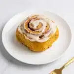 Pumpkin Cinnamon Rolls Recipe | Amazing Soft Homemade Treat 7 Pumpkin cinnamon roll with brown butter cream cheese frosting on a ceramic plate