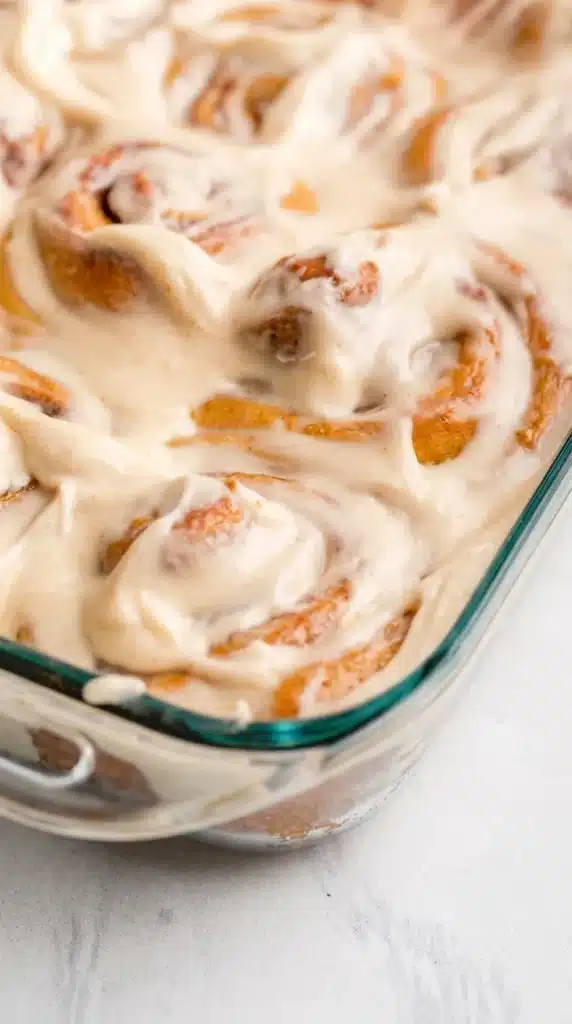 Pumpkin Cinnamon Rolls Recipe | Amazing Soft Homemade Treat 5 Pumpkin Cinnamon Rolls with cream cheese frosting in a glass baking dish