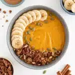 Pumpkin Pie Smoothie Bowl topped with banana, granola, pecans, and pumpkin seeds