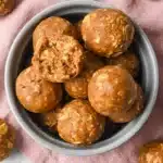 Pumpkin protein balls in a ceramic bowl with one cut open showing a soft chewy oat filled center