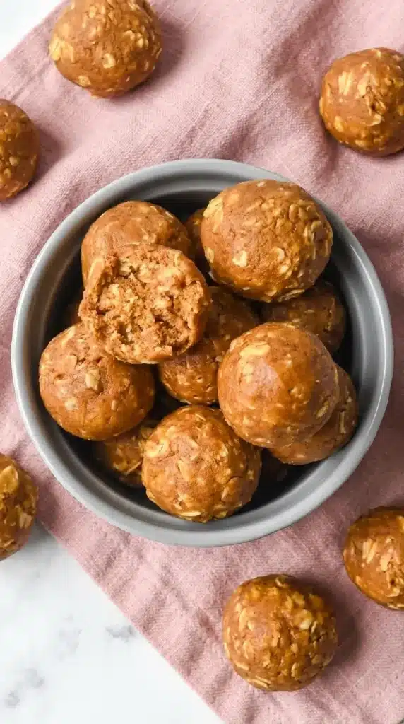 Pumpkin protein balls in a ceramic bowl with one cut open showing a soft chewy oat filled center
