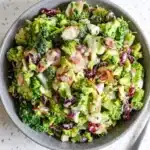 Creamy broccoli salad with bacon, cranberries, almonds, and red onion in a ceramic bowl