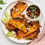 Birria Tacos with crispy tortillas, melted cheese, tender beef, consommé, cilantro, onion, and lime