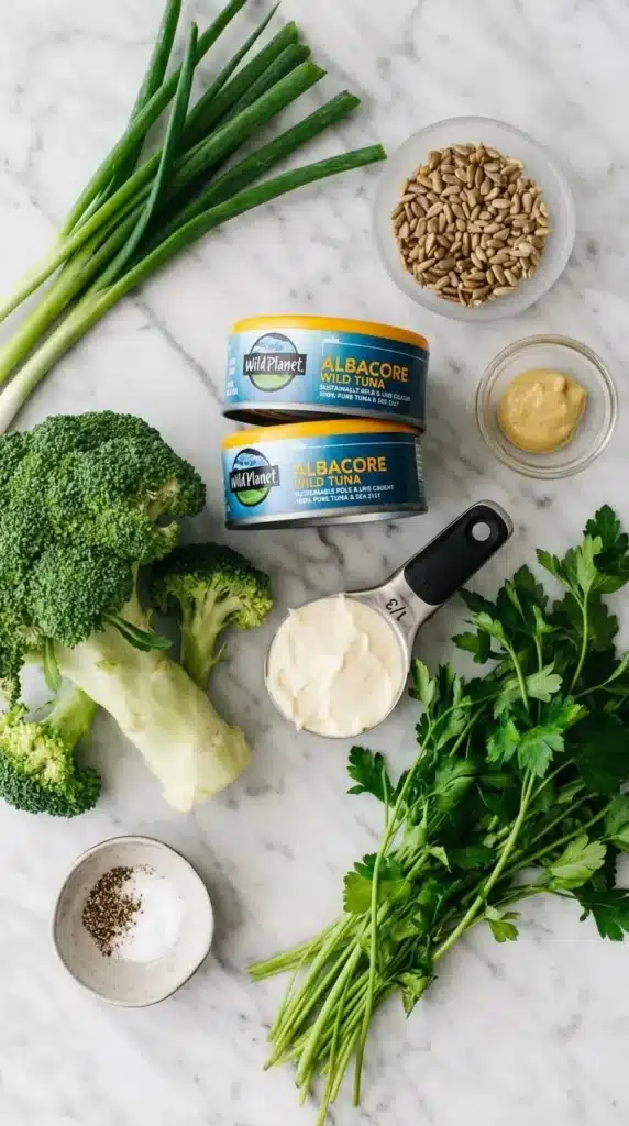 Broccoli Tuna Salad ingredients with tuna, broccoli, herbs, mayonnaise, mustard, and seeds