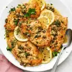 Chicken Piccata with golden chicken, lemon butter sauce, capers, parsley, and fresh lemon slices