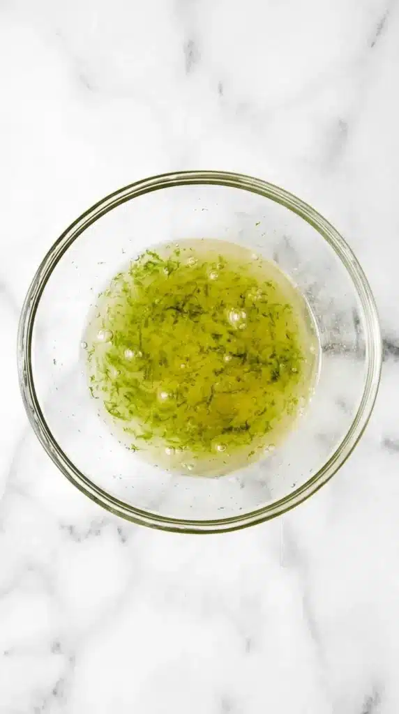Honey lime dressing for Classic Fruit Salad being whisked in a glass bowl