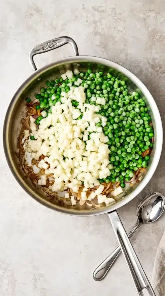 Thanksgiving Peas cooking with diced pear and sautéed shallots in a skillet