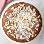 Almond Cake topped with sliced almonds and powdered sugar on a serving plate